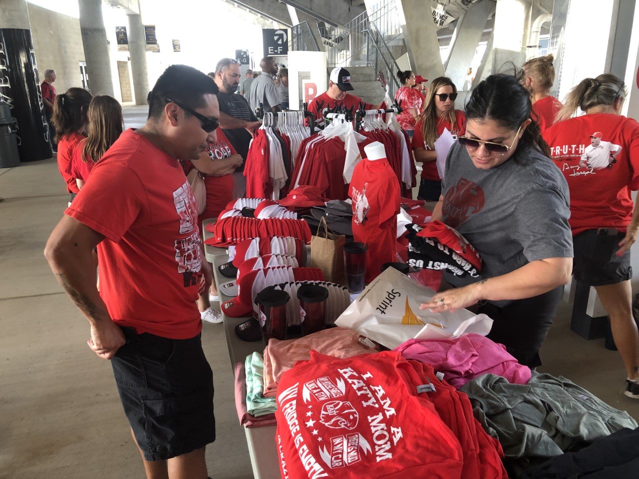 The Katy Athletic Booster Club unveiled a new line of Tiger swag at Monday’s pep rally, including a t-shirt that pays tribute to coach Gary Joseph. The shirt proclaims, “In Joseph We Trust.” Here, Tigers fan Arturo Medina purchases some swag from Booster Club volunteer Nichole Price.